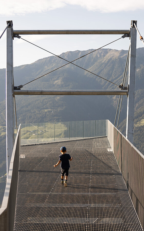 Ragazzo sulla piattaforma panoramica Unterstell con vista sulle montagne e sulla valle