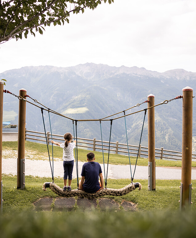 Padre e figlia che guardano attraverso un telescopio sull’intera valle e le montagne