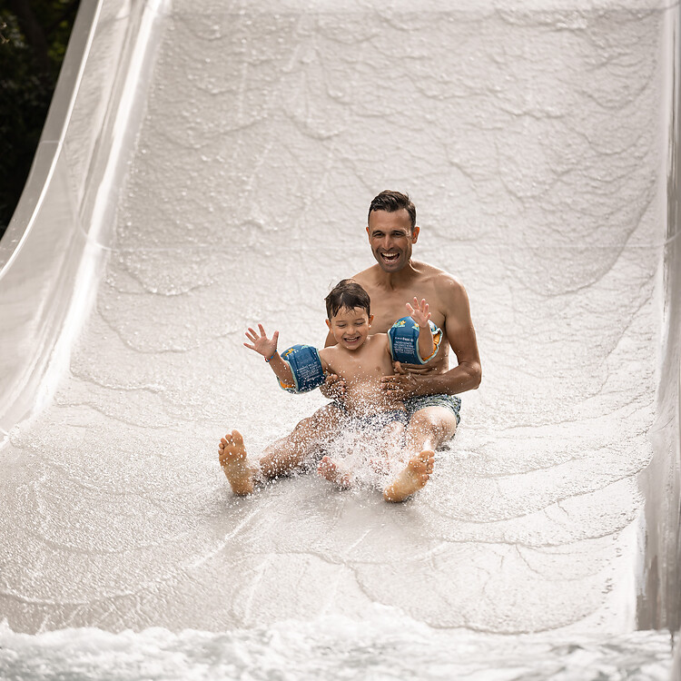 Padre e figlio che scivolano sullo scivolo a onde nel giardino