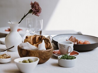 Tavola da colazione abbondantemente apparecchiata con fiori freschi