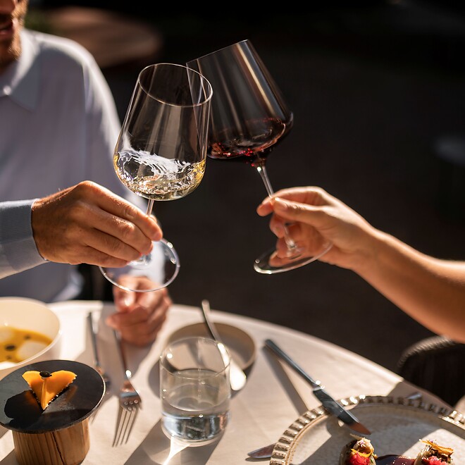 Uomo e donna brindano con un bicchiere di vino e gustano del buon cibo