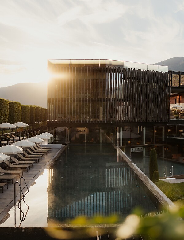 Wellnesstower con piscina sportiva e lettini prendisole all'alba