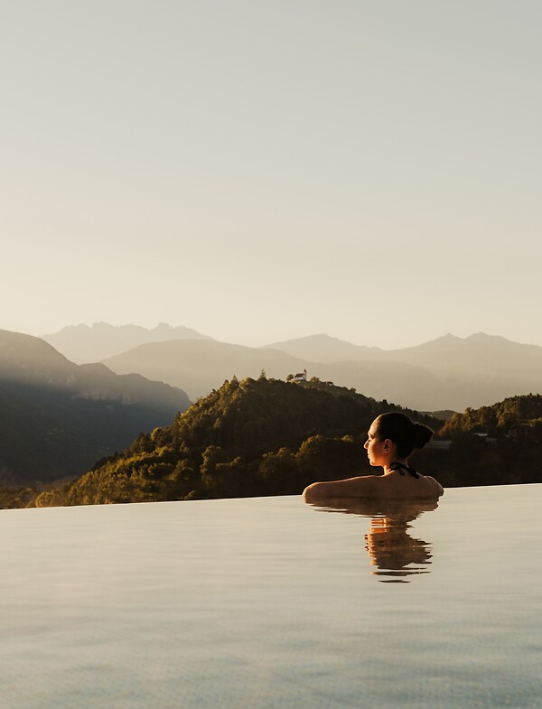 Donna che gode della vista sulle Dolomiti nell'Infinity Skypool all'alba