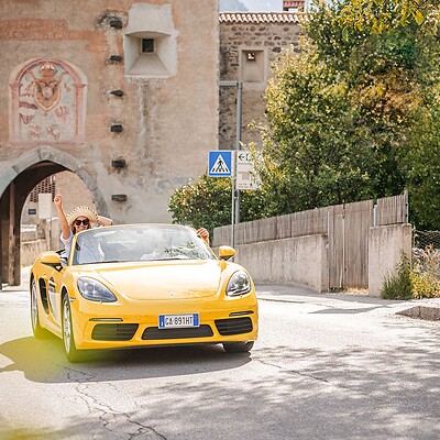 Donna in Porsche Cabrio giallo attraversa un portale delle antiche mura cittadine