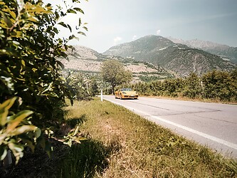 Porsche Cabrio giallo su strada nel cuore delle Alpi