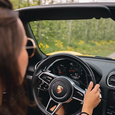 Donna al volante di una Porsche Cabrio