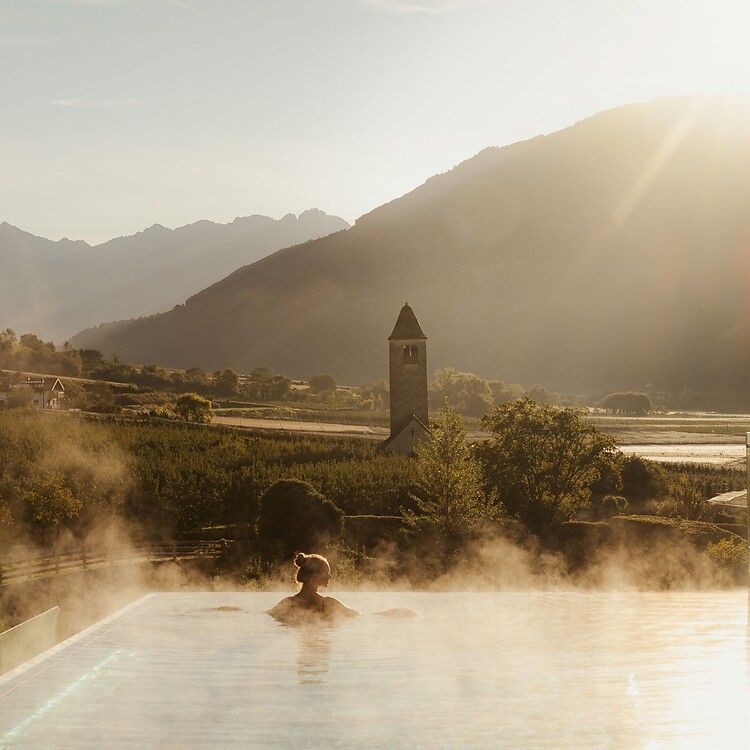 Frau genießt im Infinity Skypool die traumhafte Aussicht bei Sonnenaufgang