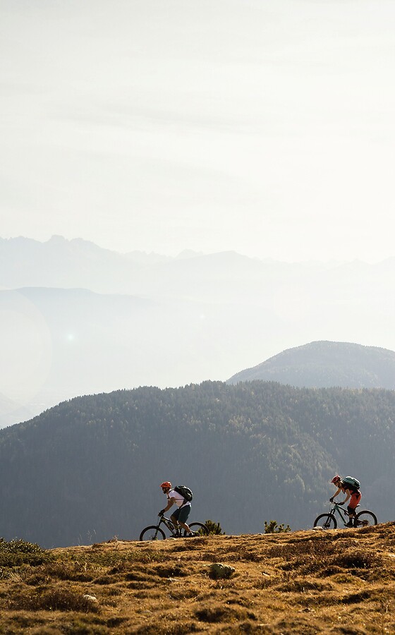 Gruppe fährt mit E-Mountainbikes über Bertrail vor Bergpanorama