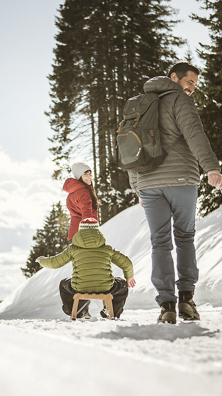 Famiglia che slitta su pista forestale