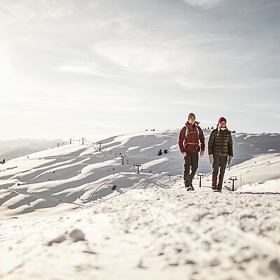 Uomo e donna in montagna sulla neve passando vicino a seggiovia