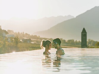 Uomo e donna nella Sky Infinity Pool con luce serale romantica