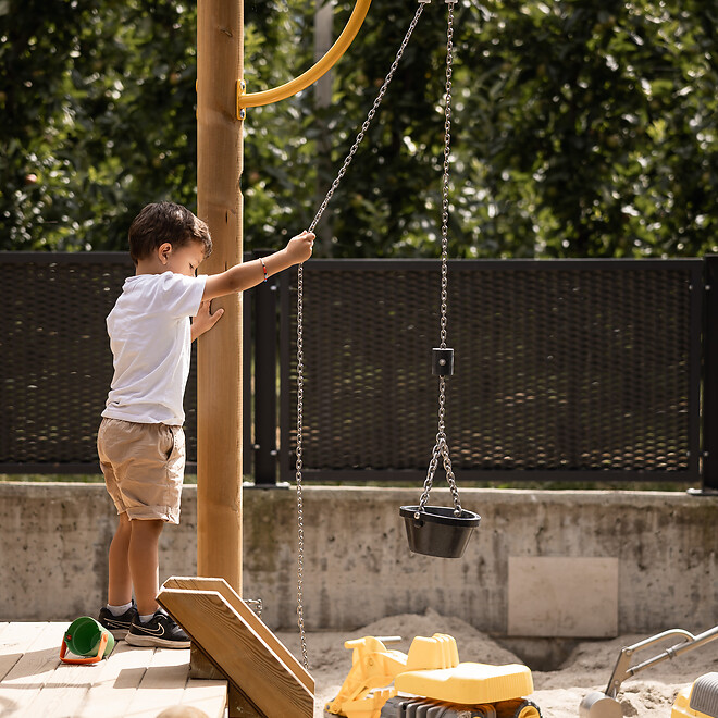 Kind spielt im Sandkasten im hoteleigenen Outdoor-Spielplatz