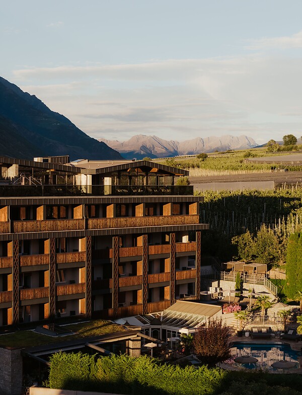 Hotel facade with pool and garden surrounded by the mountains in Val Venosta