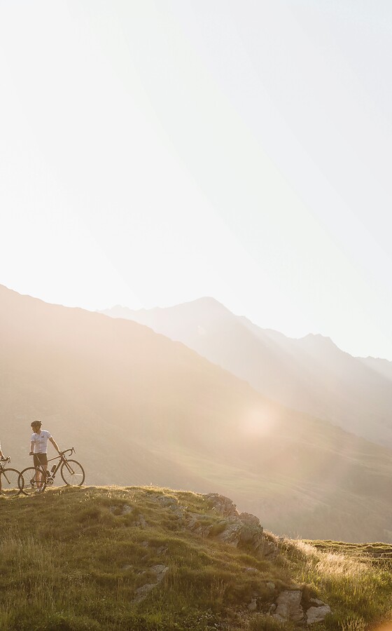 Donna e uomo con bicicletta in montagna al tramonto