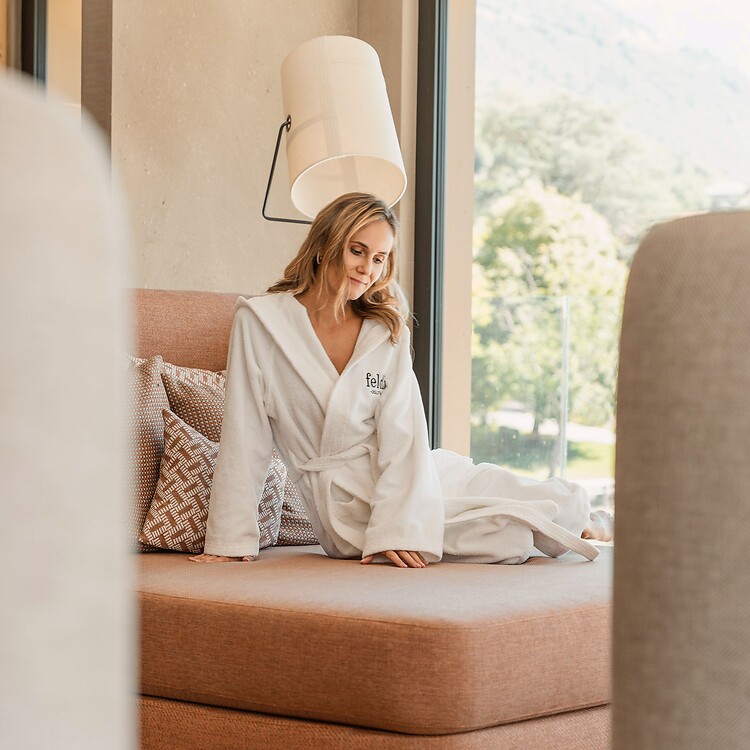 Woman relaxing on a red lounge chair in the relaxation room at the Sky Spa