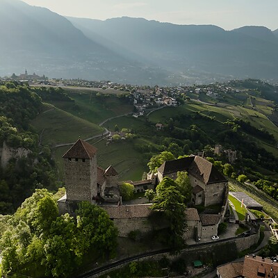 The medieval Tyrol Castle surrounded by mountains and green meadows