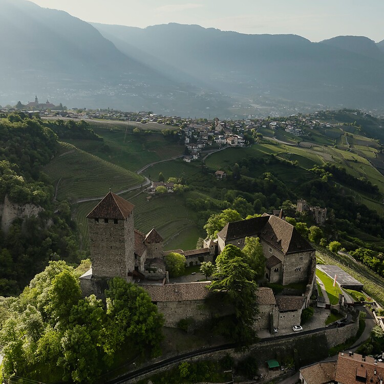 The medieval Tyrol Castle surrounded by mountains and green meadows