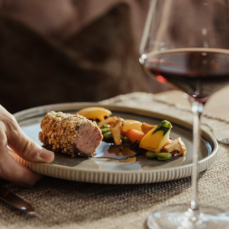 The waiter serves dinner with a glass of red wine