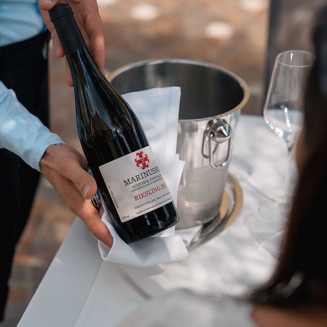 The waiter serves the guest the hotel’s own wine