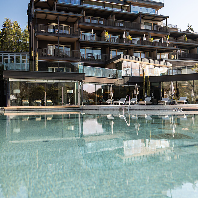 Hotelfassade und Naturpool im Garten