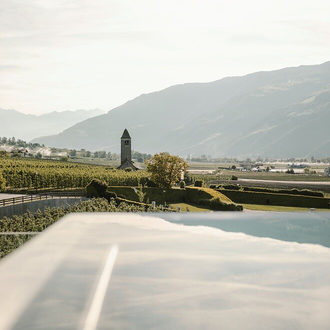 Sky Infinity pool with thermal pool in front of mountain panorama and view of Proculus Church