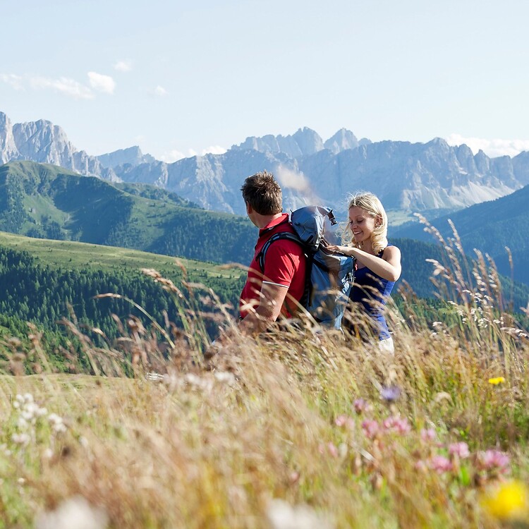 Man and woman hiking through the blooming alpine meadows of the Dolomites