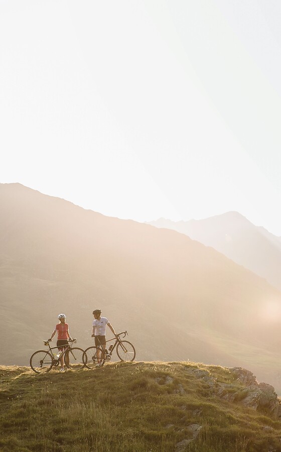 Woman and man with bike in the mountains at sunset