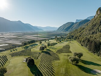 Drone shot of golf course between apple orchards and mountains
