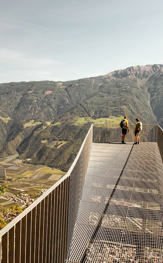 Man and woman on Unterstell viewing platform with view over valley and mountains