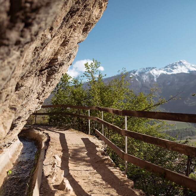 Irrigation channel trail with view of snow-covered Alpine peaks