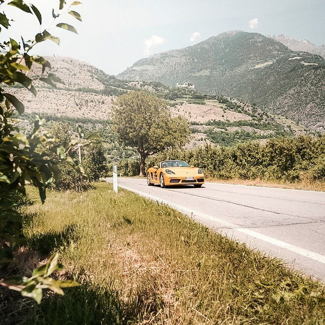 Yellow Porsche convertible on road in the middle of the Alps