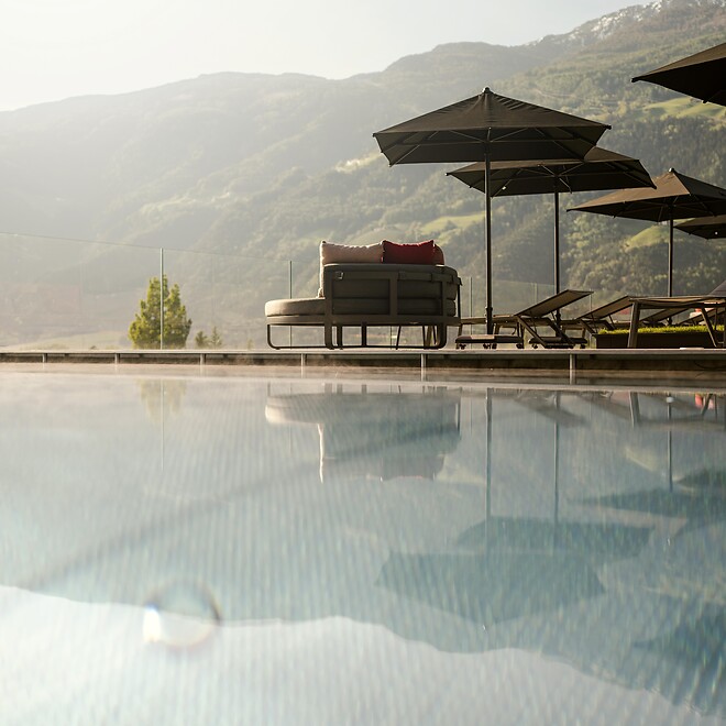 Pool with lounge chair and sun umbrella with mountain views and low sun