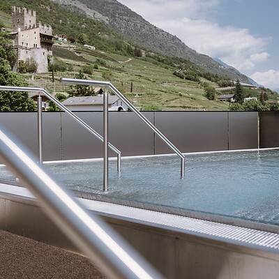 Nude pool in the Sky Spa with mountain panorama and medieval castle backdrop