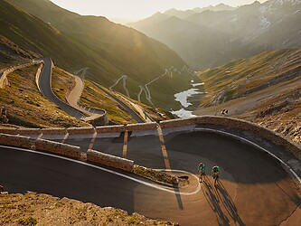 Cyclists riding the switchbacks of Stelvio Pass in the low evening sun