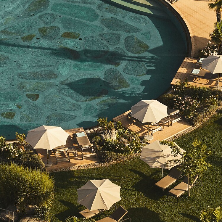 Natural pool with sun loungers in the Mediterranean hotel garden