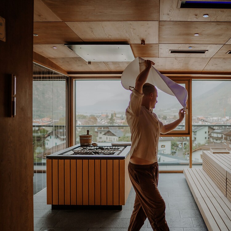 Sauna master performing a sauna infusion in the panoramic sauna at the Sky Spa