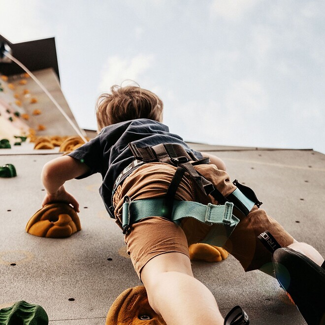 Kind klettert an Outdoor Kletterwand im Hotel hoch