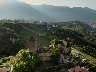 das mittelalterliche Schloss Tirol inmitten von Bergen und grünen Wiesen