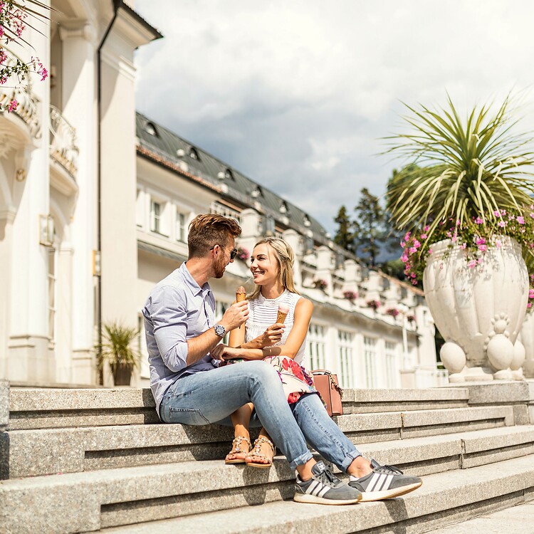 Frau und Mann essen Eis auf Treppe des Kurhauses in Kurstadt Meran