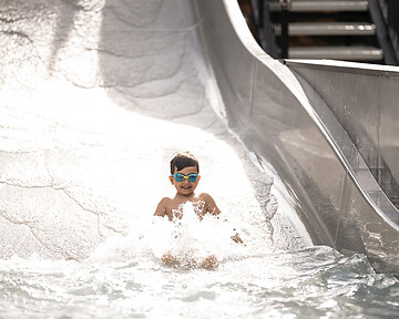 Kind auf der Wellenwasserrutsche im Hotelgarten