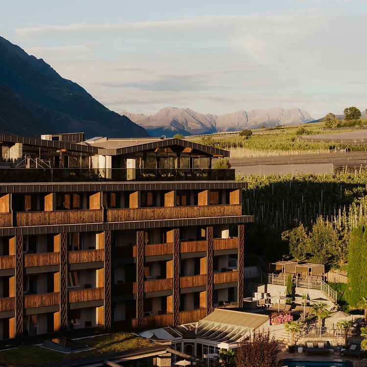 Facciata dell'hotel con piscina e giardino circondata dalle montagne in Val Venosta