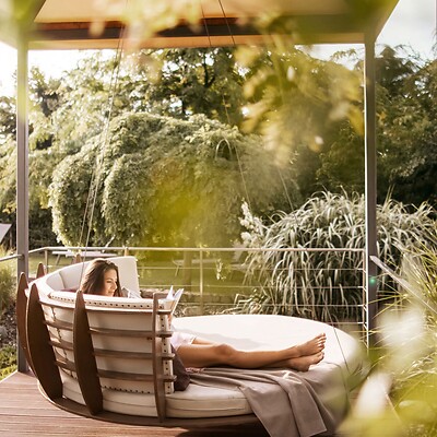 Frau liest in den Hängeliegen im Hotelgarten