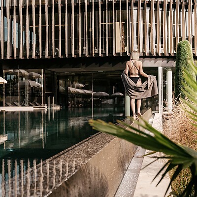Frau spaziert entlang des Outdoor Pools vor dem Wellnesstower
