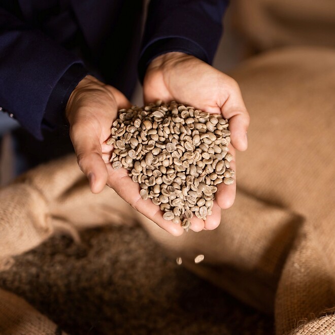 Uomo con chicchi di caffè tostati in mano