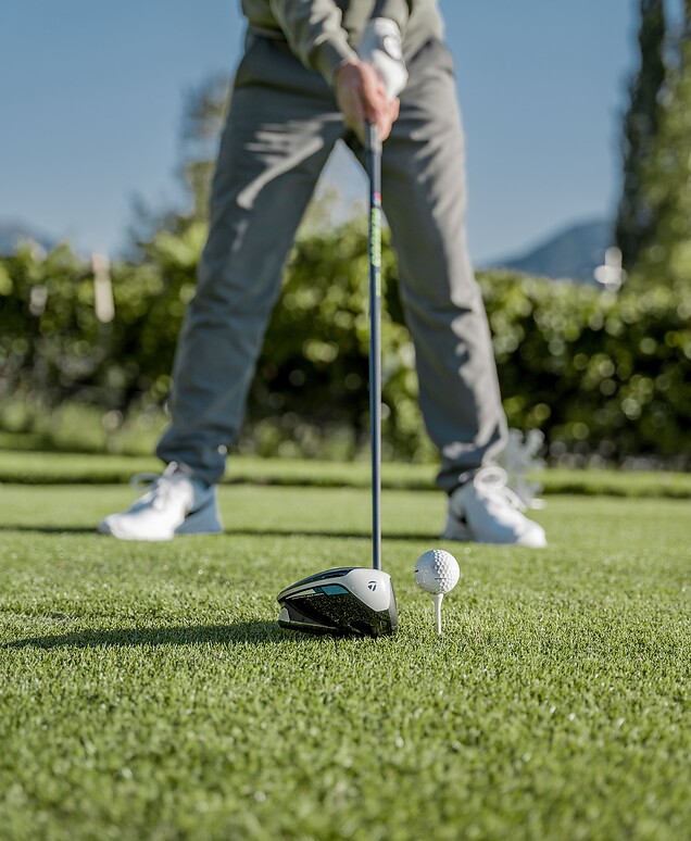 Man holding golf club ready over golf ball for tee shot