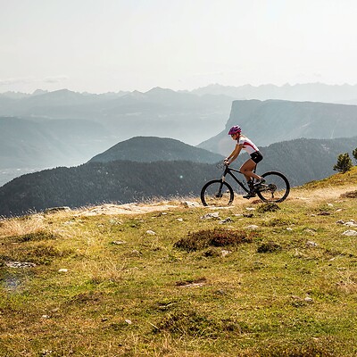 Woman riding an e-mountain bike on a mountain trail with mountain views