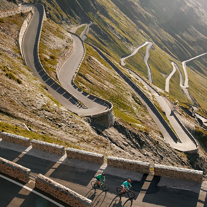 Cyclists riding the switchbacks of Stelvio Pass in the low evening sun