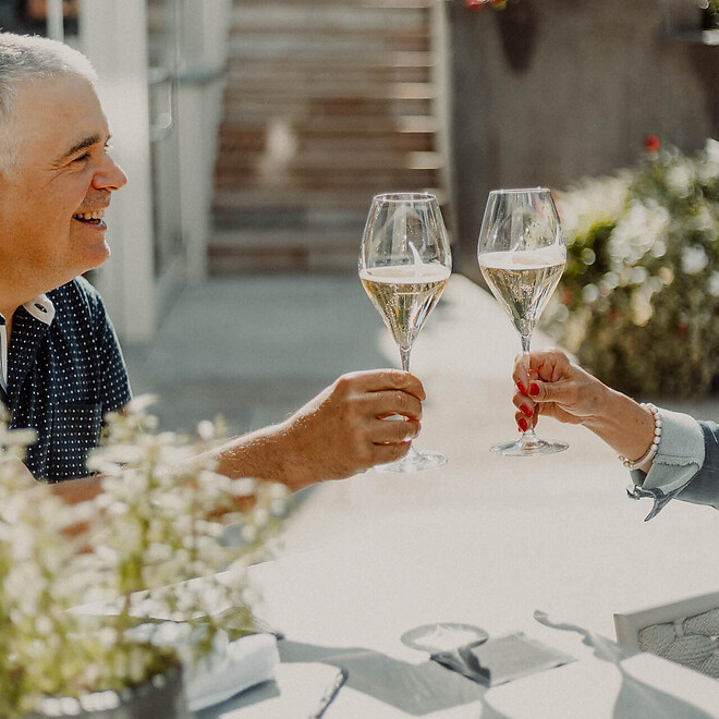 Guests toasting with a glass of sparkling wine on the sunny terrace