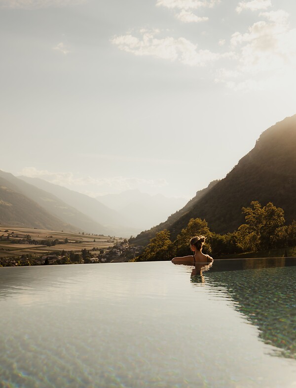 Donna che gode della vista panoramica nell'Infinity Pool al tramonto