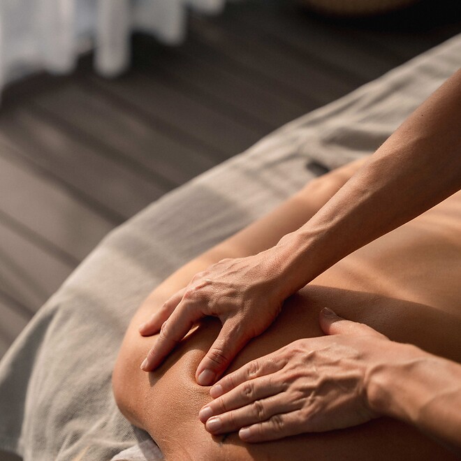 Frau erhält Rückenmassage bei sanft einfallenden Sonnenstrahlen